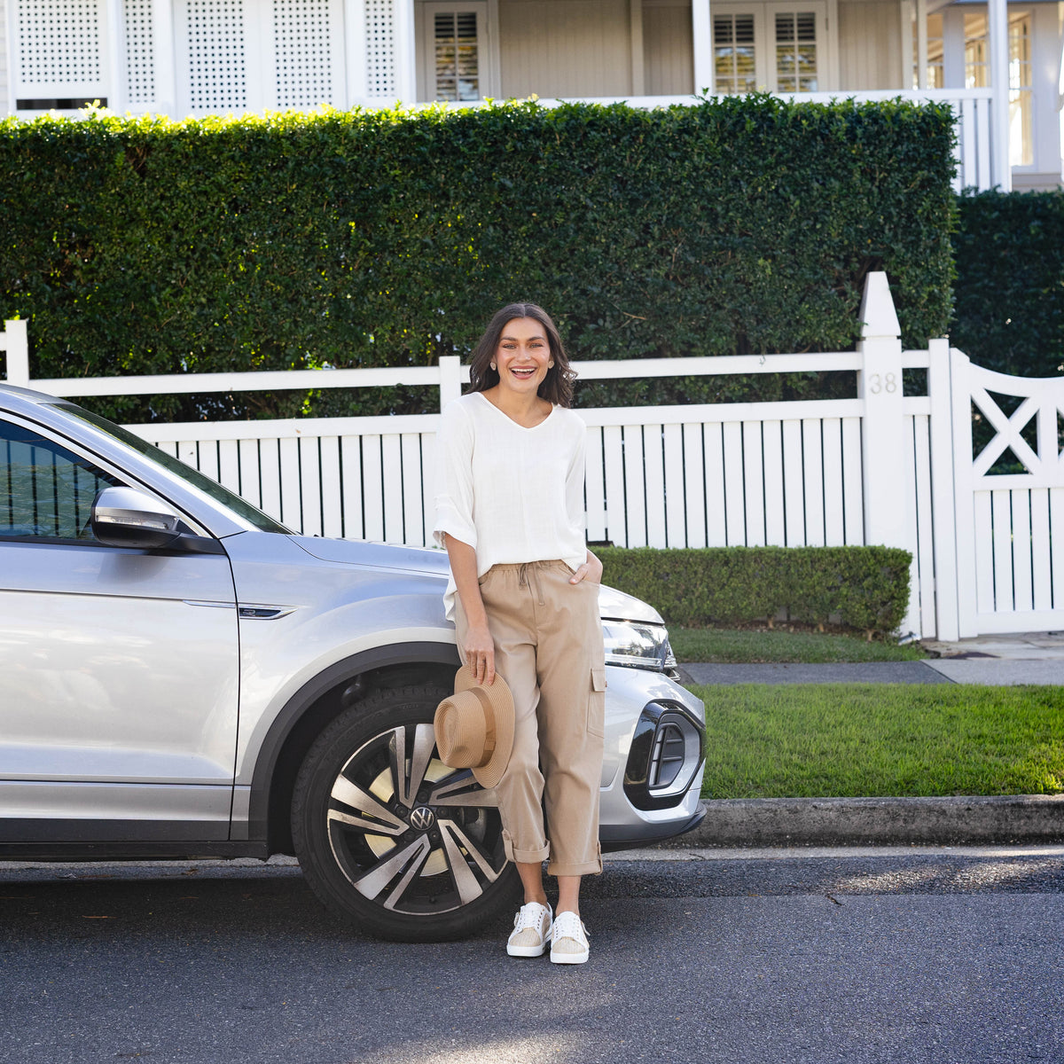 Brunette model wearing a comfortable road trip outfit in front of a car.