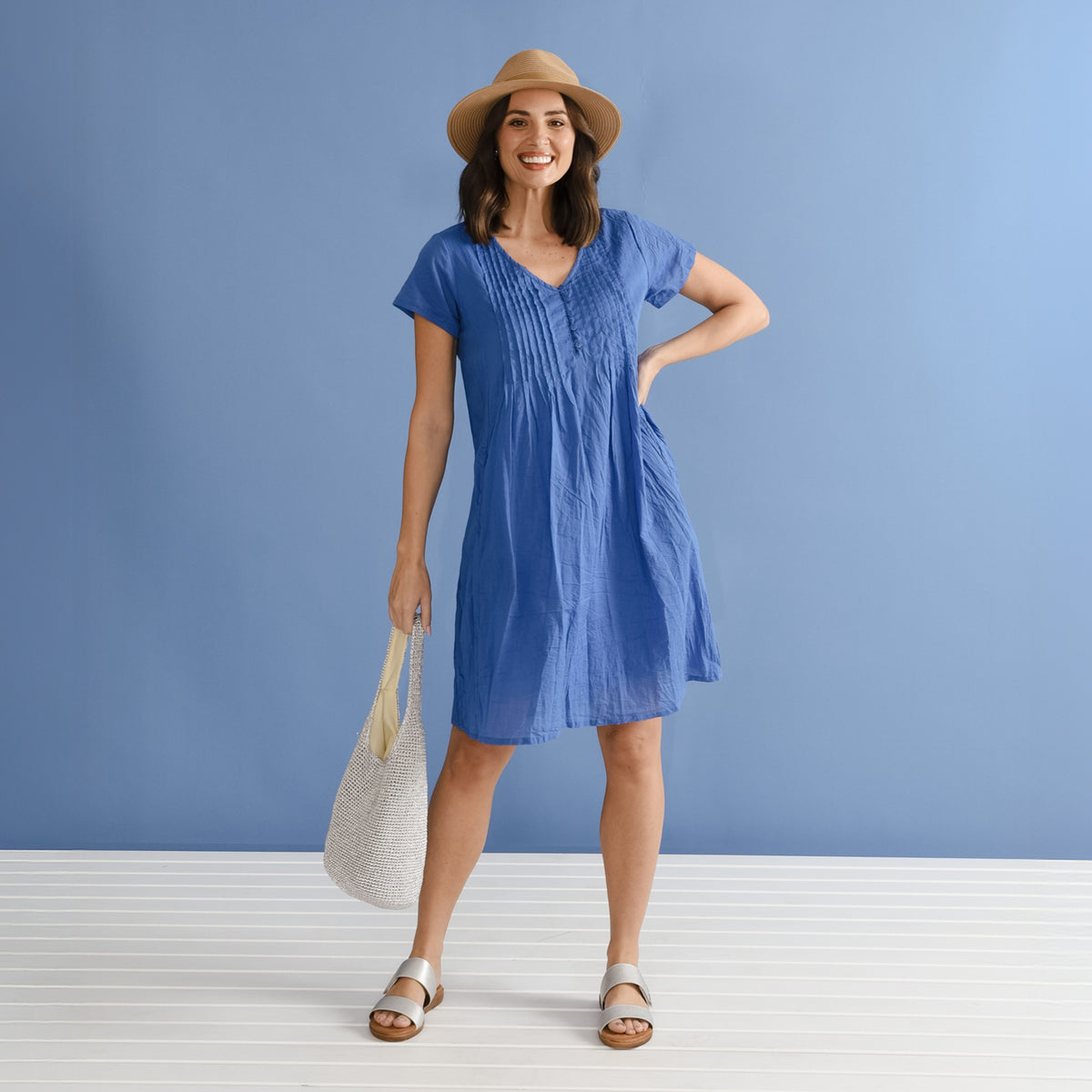 Brunette woman in a blue crinkle no-iron cotton knee-length dress.