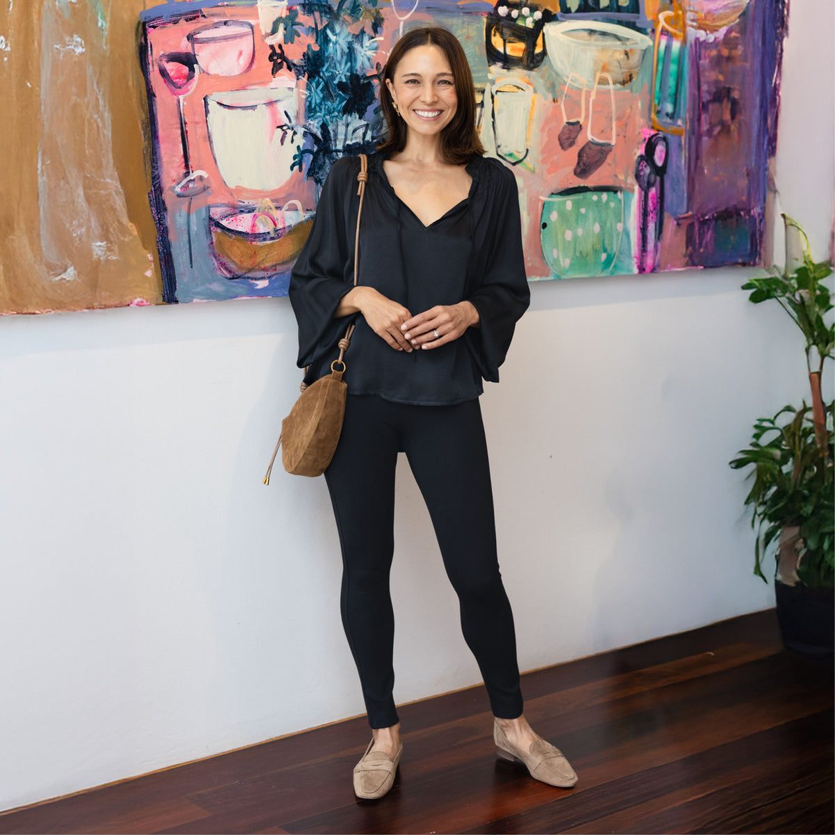 Brunette woman in smartly styled fitted black ponte pants with beige loafers and a long sleeve charcoal top.