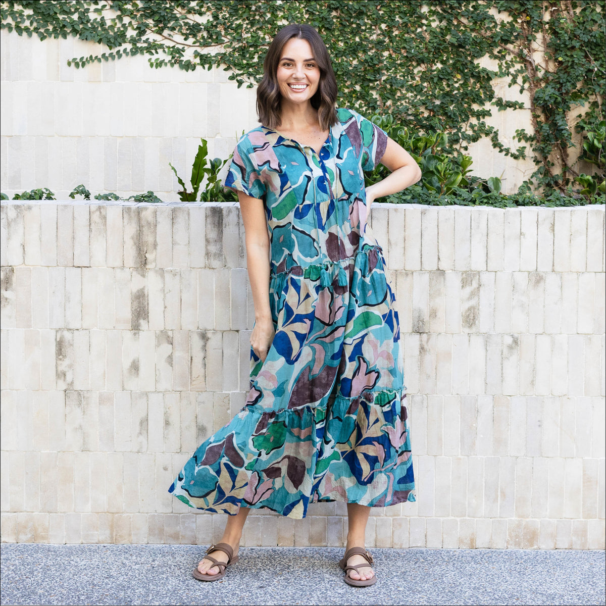 Brunette woman in a blue print long travel dress with brown sandals