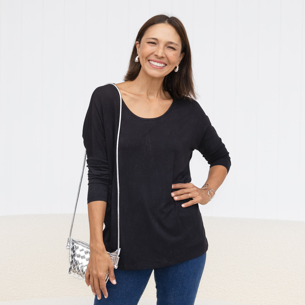 Brunette woman in a black scoop neck draped top