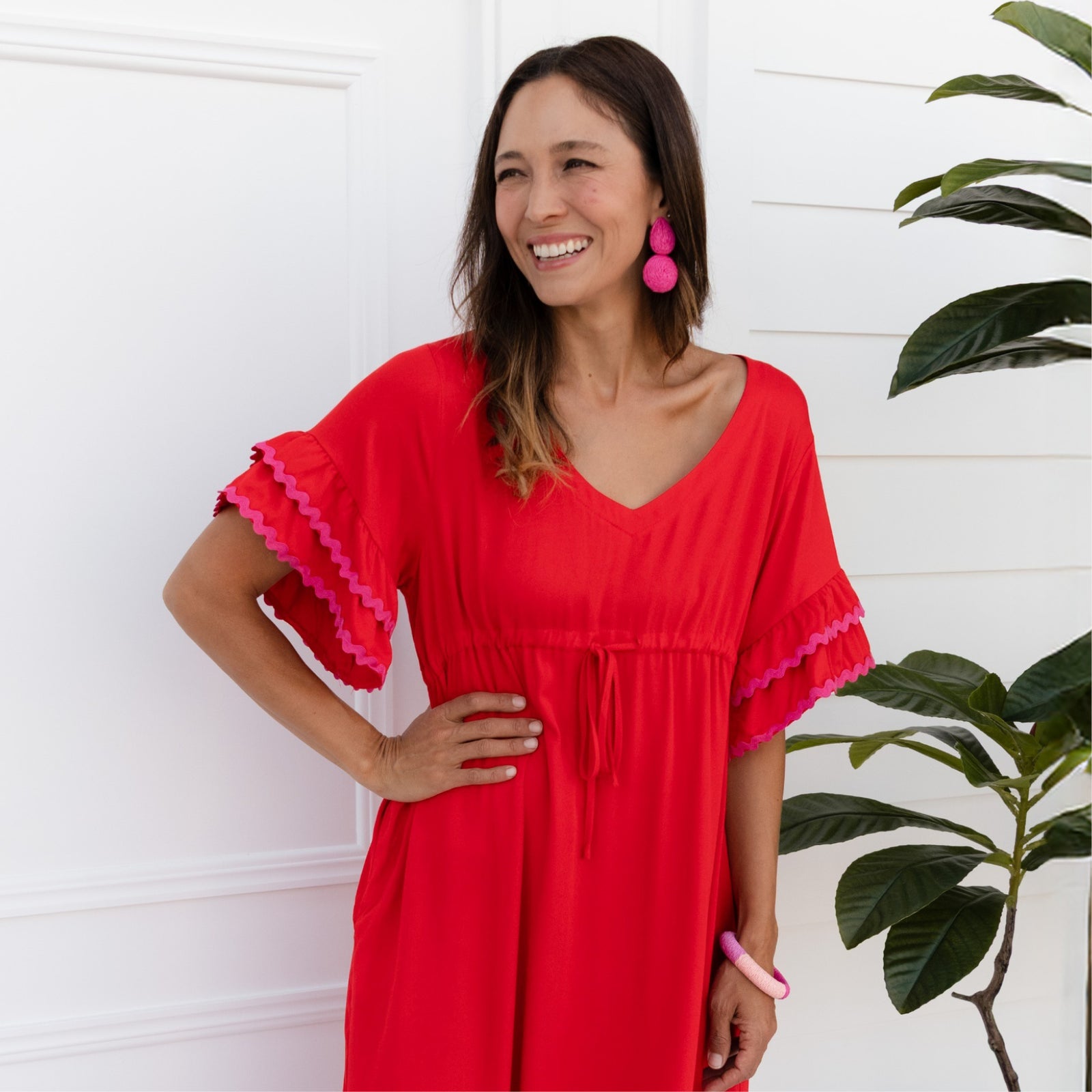 Brunette woman in a red dress smiles and looks to the side.