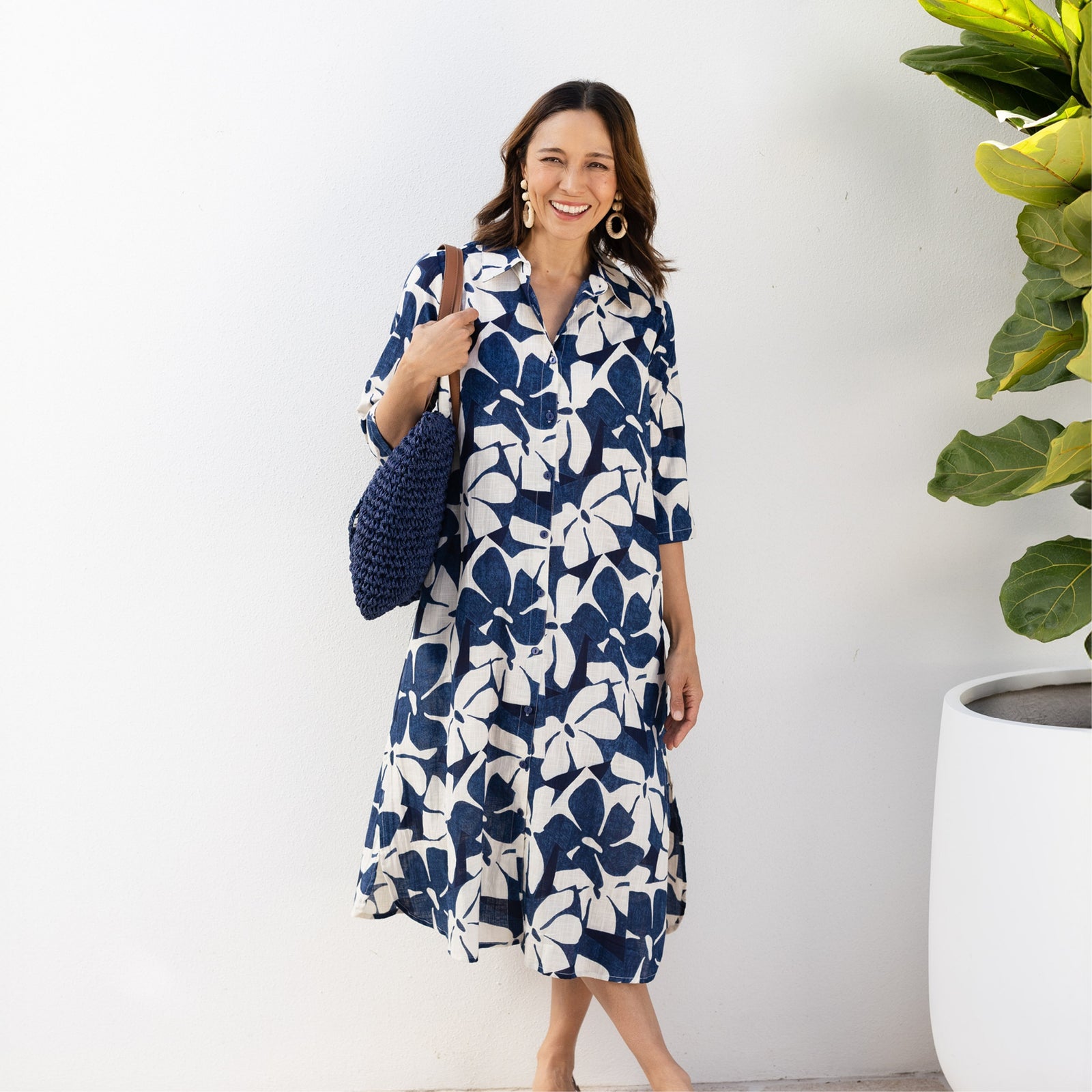 Brunette woman stands wearing a blue and white floral shirt dress with sleeves and a skirt below the knee, suitable for petites.