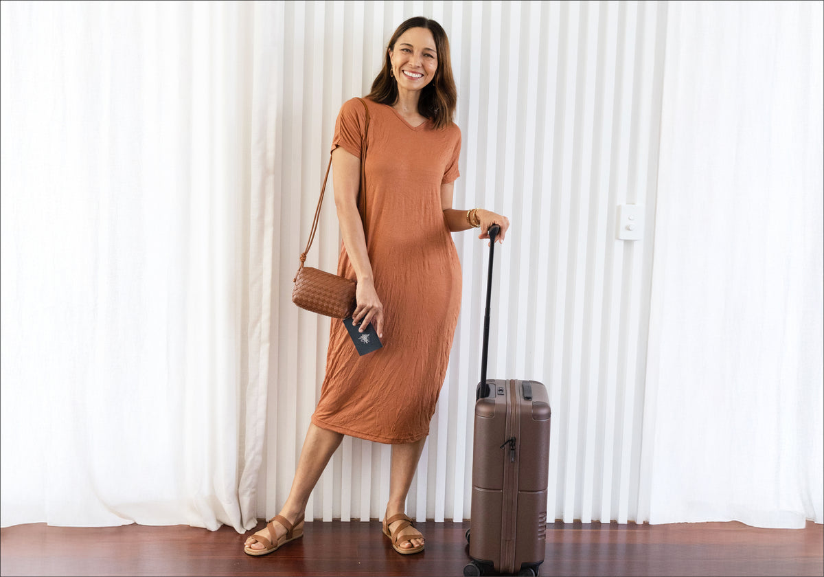Brunette woman in Travel No-Iron textured stretchy dress in rust colour with V-neckline