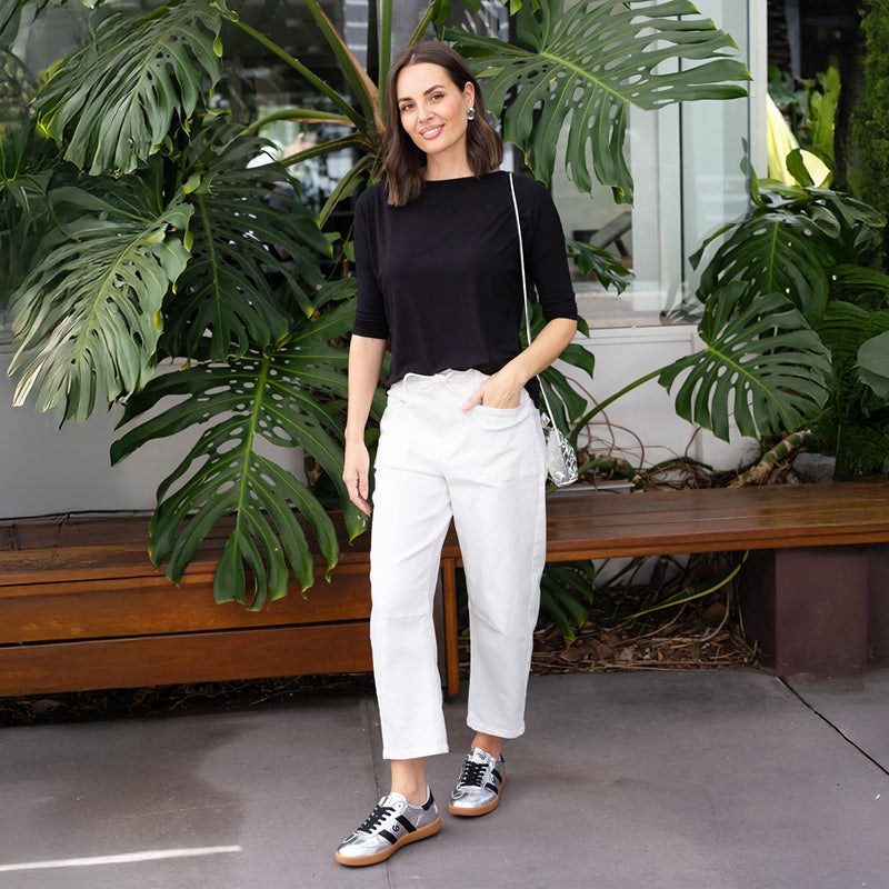 Brunette woman wearing white barrel pants and a black top
