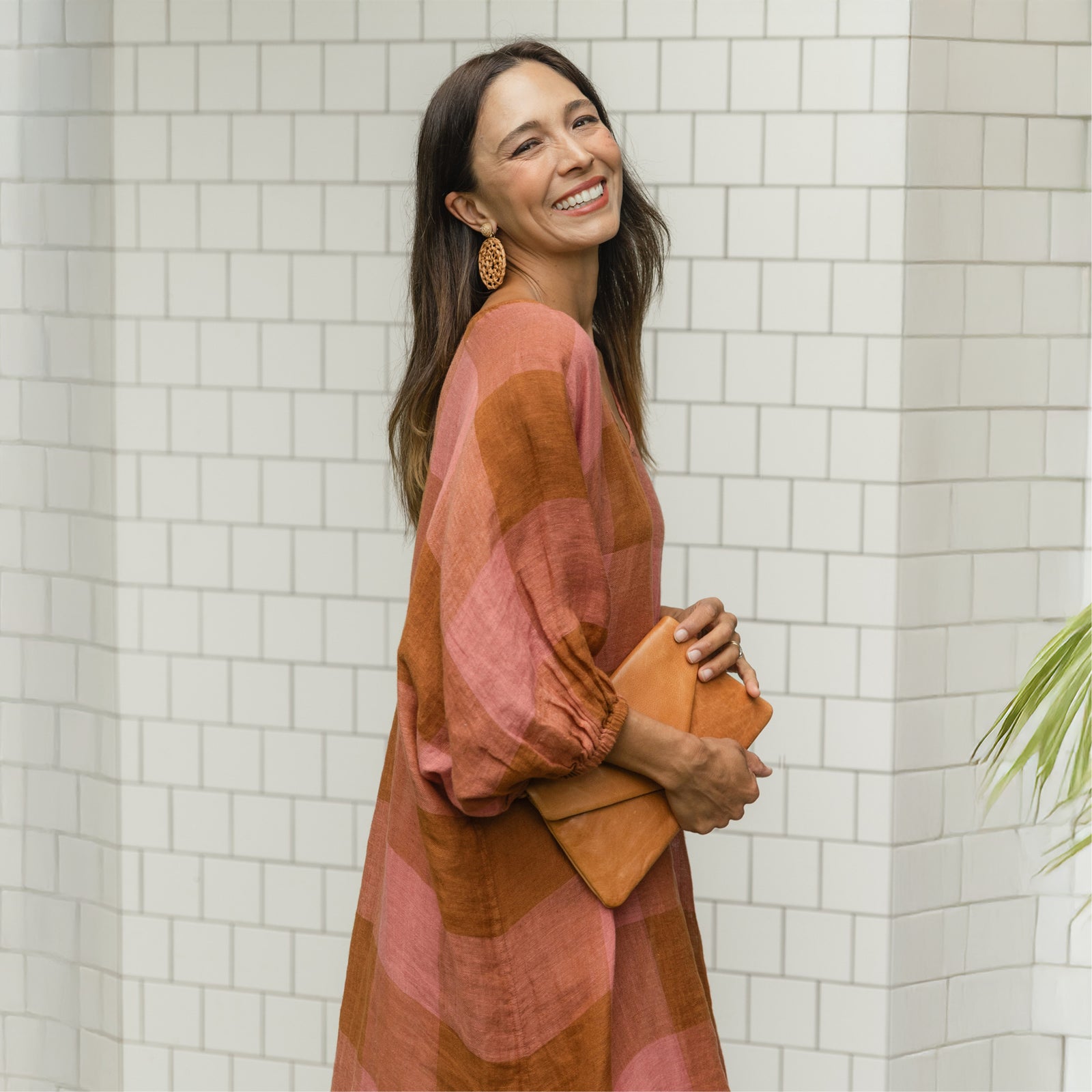Brunette woman in muted orange and pink kaftan dress smiles broadly.