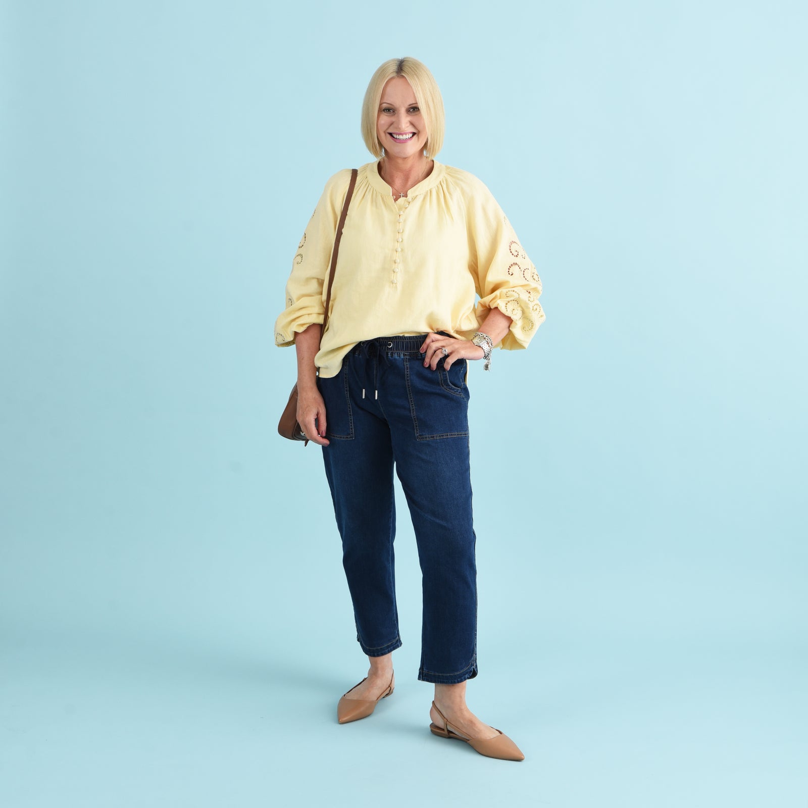 Blonde woman wearing blue denim jeans and a yellow blouse.