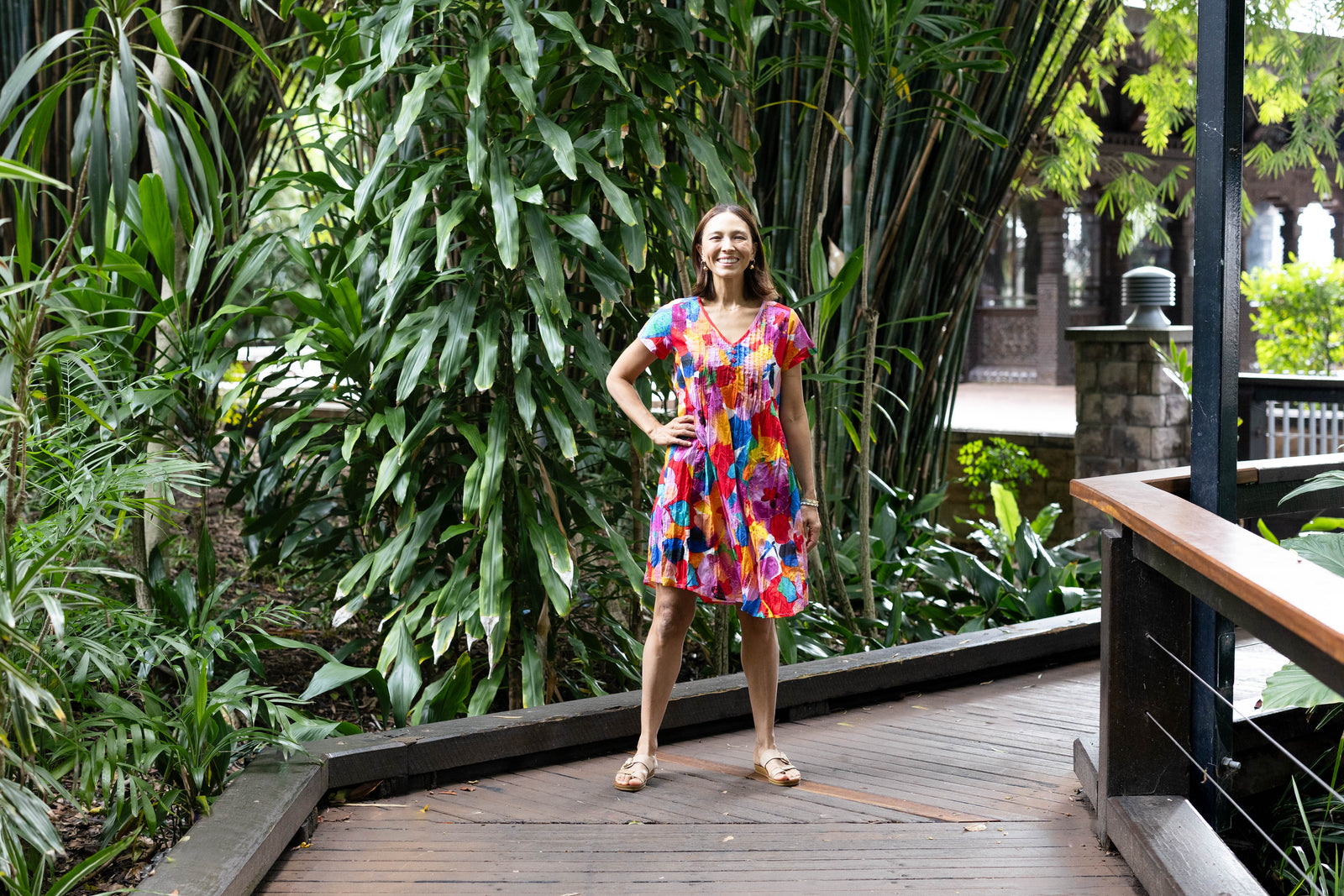 Brunette woman wearing a pink, orange and blue floral print no iron crinkle cotton dress.